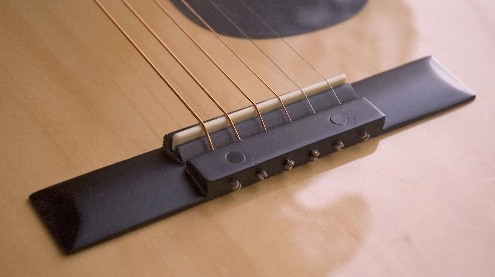 The bridge of an acoustic guitar, glued to the top. Check whether its edges are lifting. Photo: The Last V8, CC BY-SA 2.0
